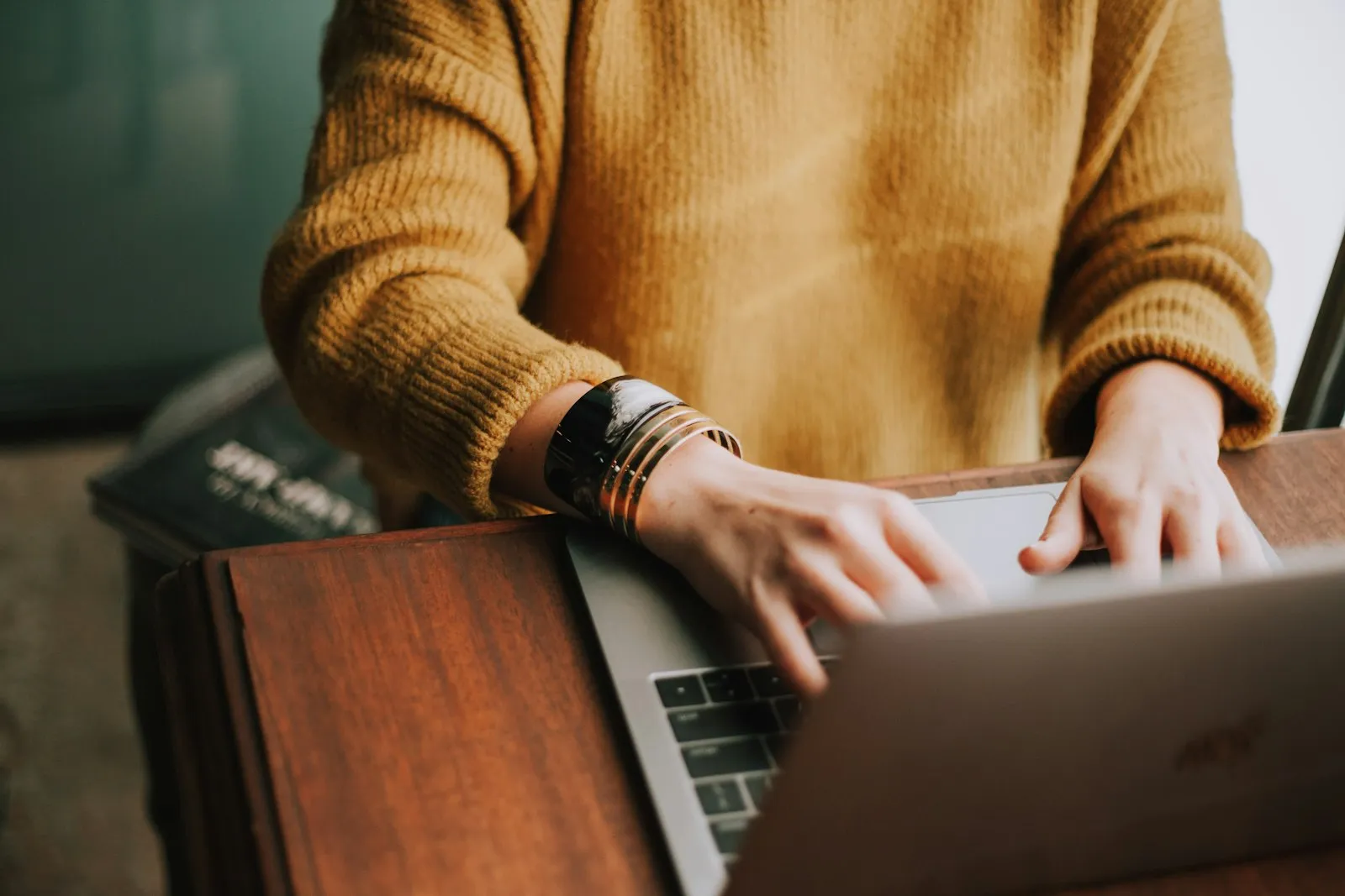 A person typing on a laptop at a wooden desk