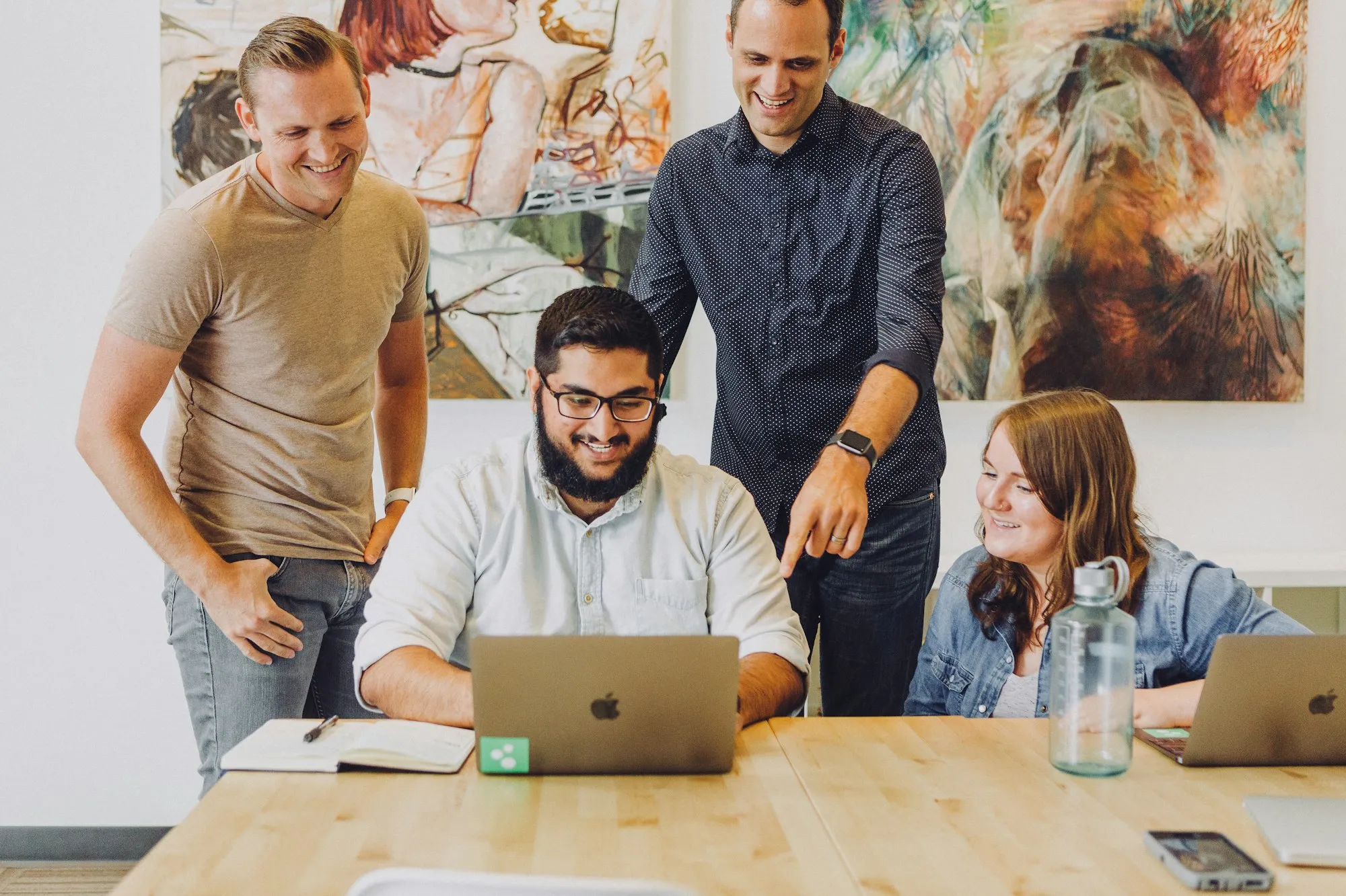 Colleagues smiling while working together around a laptop