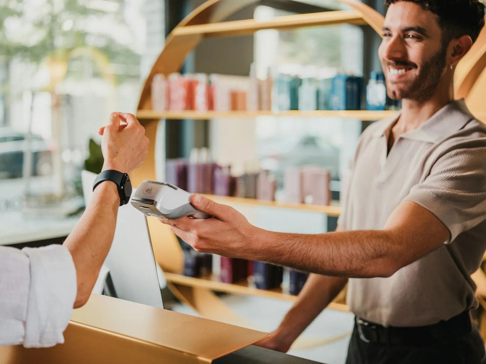 A customer paying at a shop counter while the owner smiles