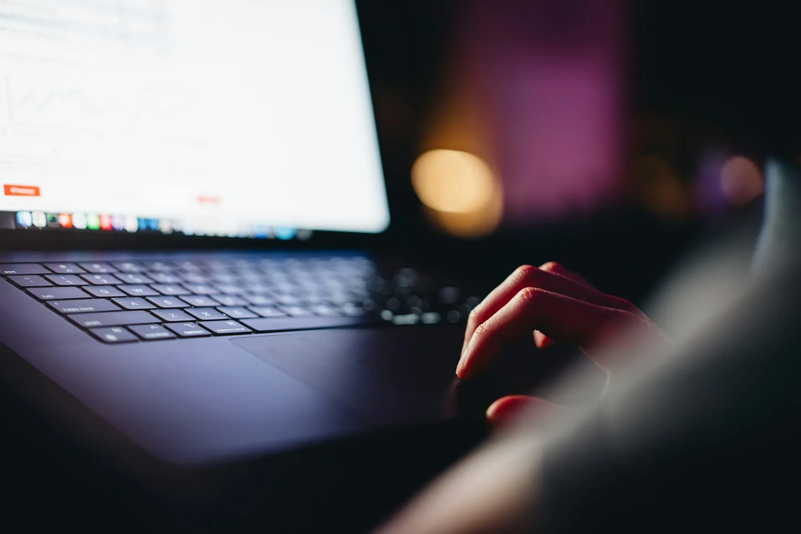 A person working on a laptop in a dimly lit room