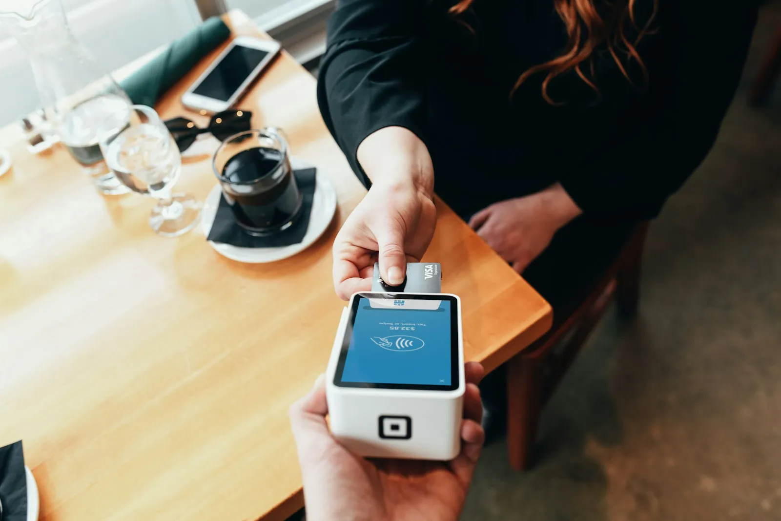 A customer paying by card on a mobile payment terminal in a cafe