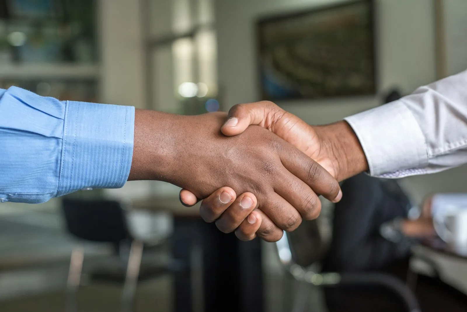 Two people shaking hands across a desk