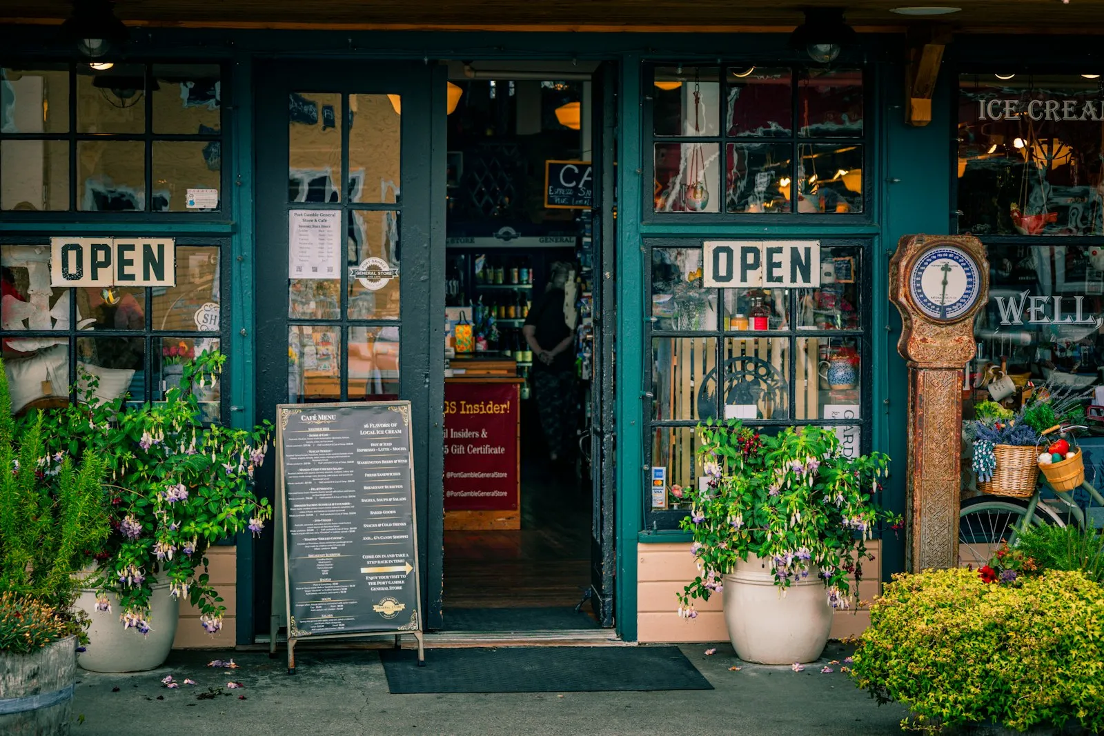 A small shop front with open signs and plants
